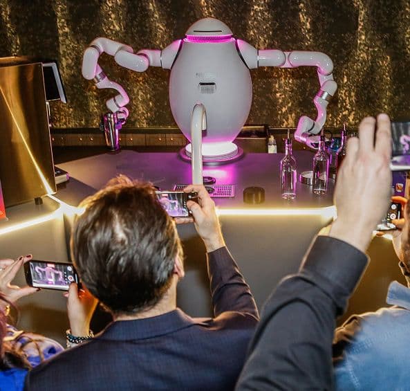 people surround and take photos of a bartender robot